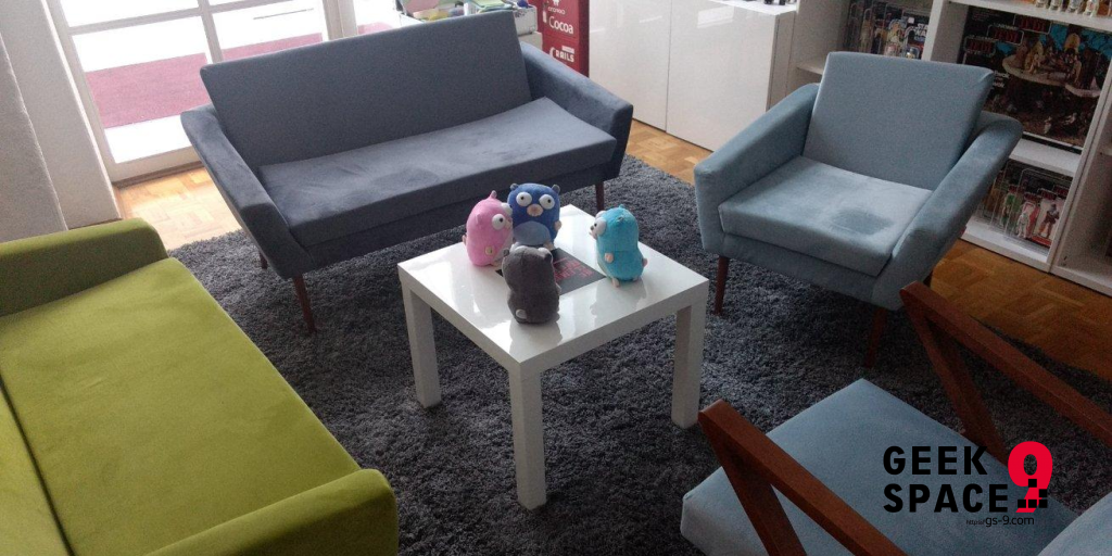 4 gophers sitting on a low table in centre of a green and a grey couch and 2 blue armchairs, grey carpet on the floor, shelves in the back with action figures